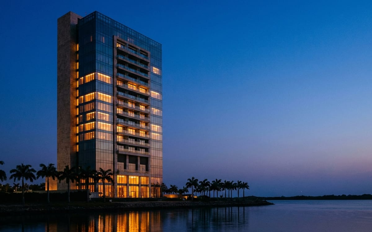 Waterfront hotel tower at dusk on the Lagos lagoon, lights coming on floor by floor